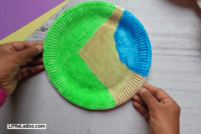 Painting the paper plate in green, blue and brown to make our farm craft