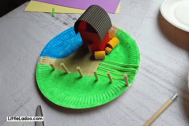 Fixing the hay and barn on the paper plate to completely set up our farm